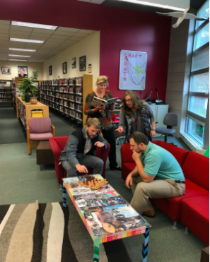 FRIENDLY GAME- New staff at South poses for a funny picture with one another. Mr. Doug Arthur and Mr. Dan Drida compete in a friendly chess game, while Ms. Sandra Botham reads a book and Ms. Melissa McCaman watches the chess game. 