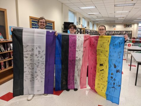 GSA advisor Ms. Vogt, GSA president Cam Livermoore, and social studies teacher Mr. Rossmiller holding up the flags that students were encouraged to sign on Day of Silence to show their support for the LGBTQ+ community.
